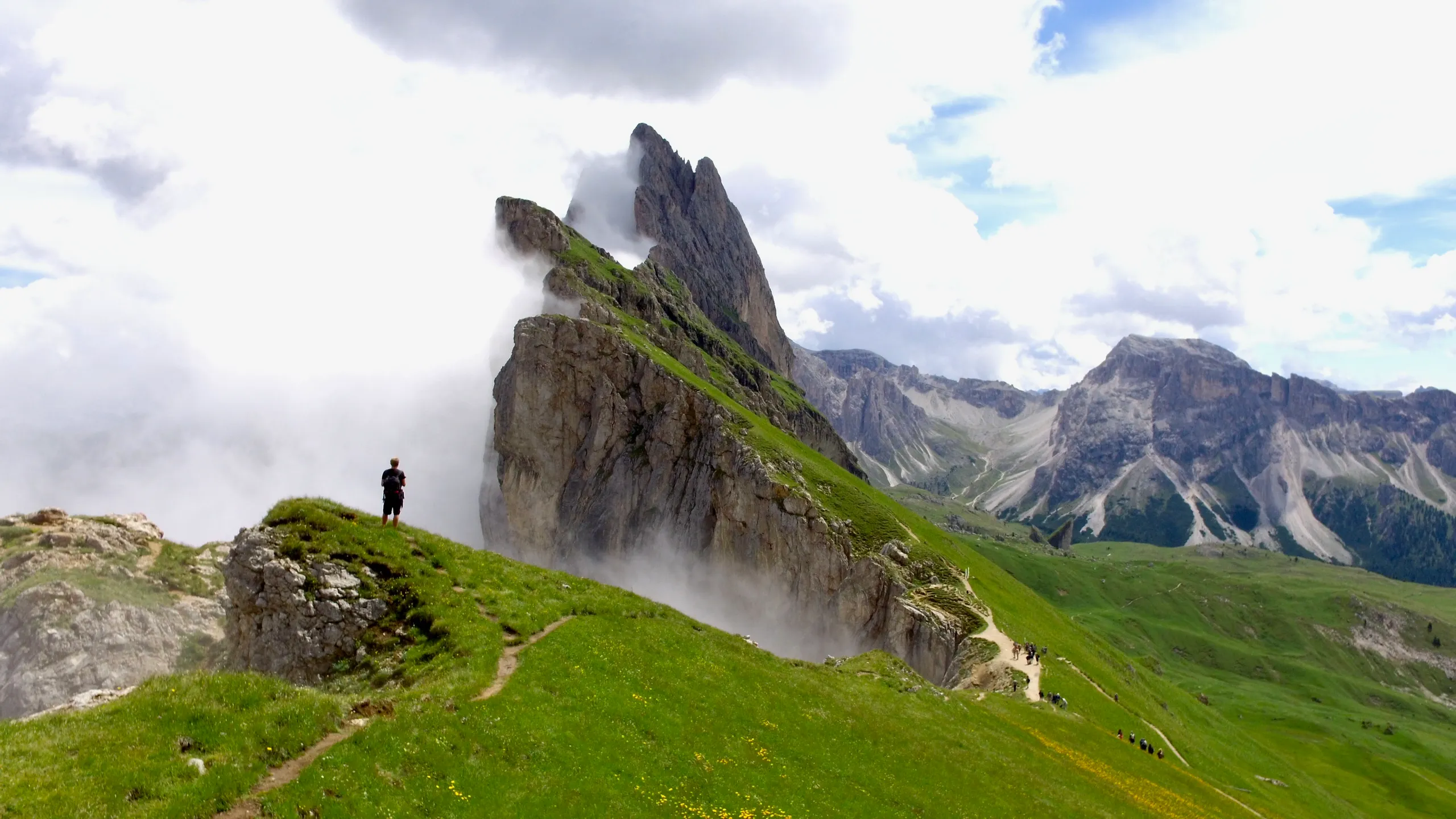 A hiker standing on an Alpine mountain ridge above the clouds